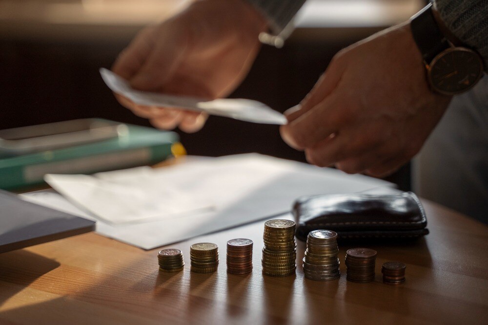 Mesa com moedas. documentos, carteira e homem organizando