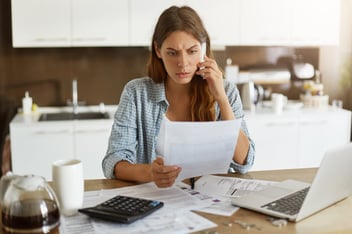 Mulher ao telefone e com documento nas mãos, possivelmente tentando evitar a inadimplência. 