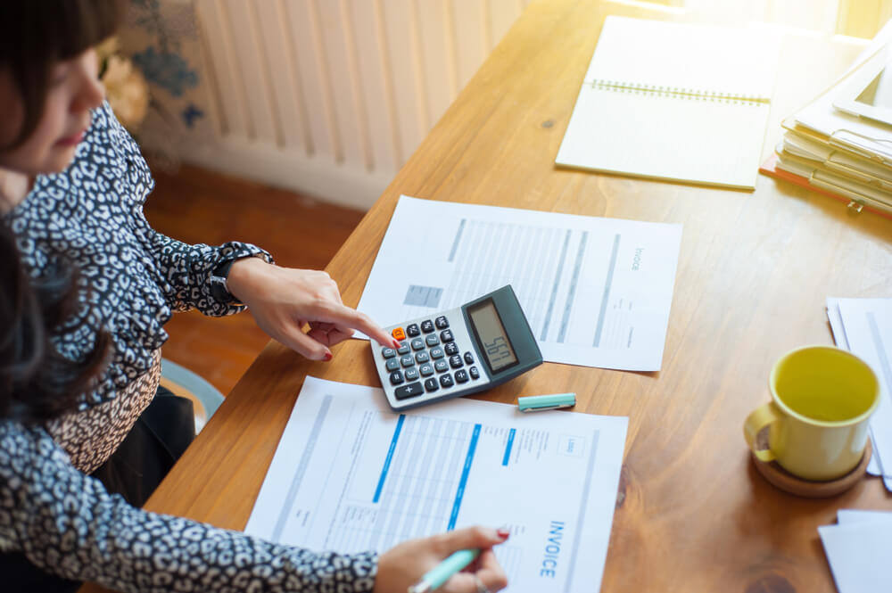 mulher mexendo em uma calculadora em cima de uma mesa